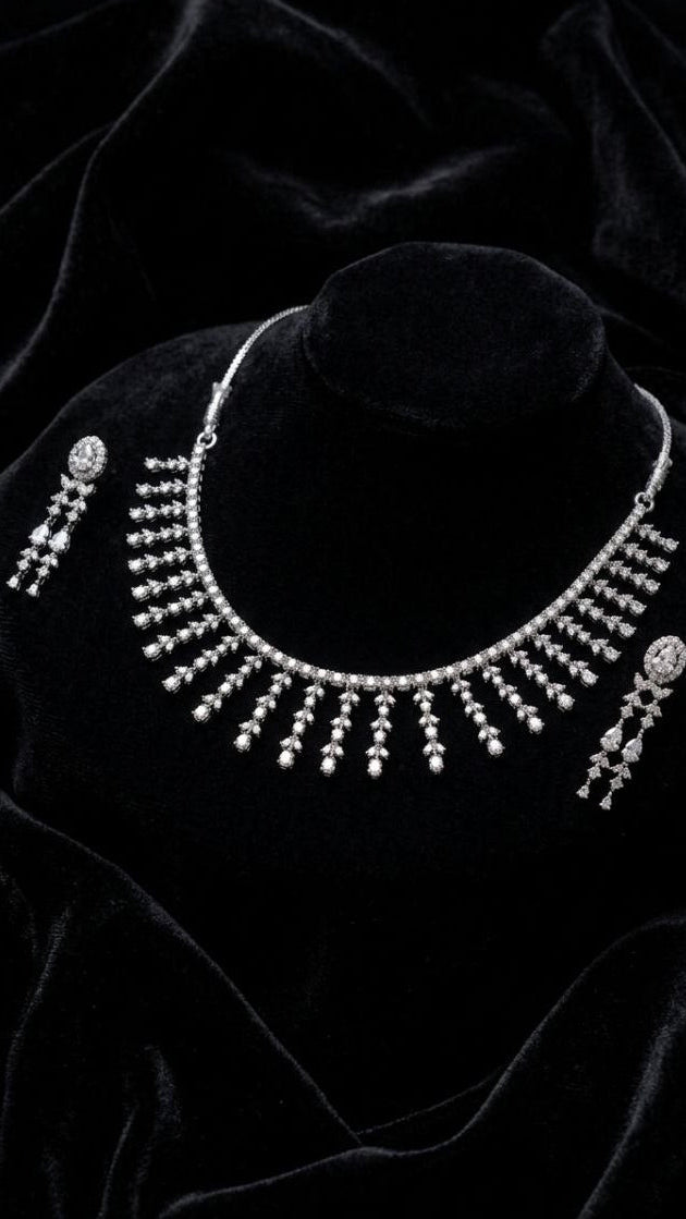 Premium silver fringe necklace with cascading crystal tassels and matching drop earrings displayed on white velvet fabric 3