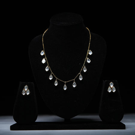Classic teardrop Polki diamond necklace set with matching earrings displayed on black stand