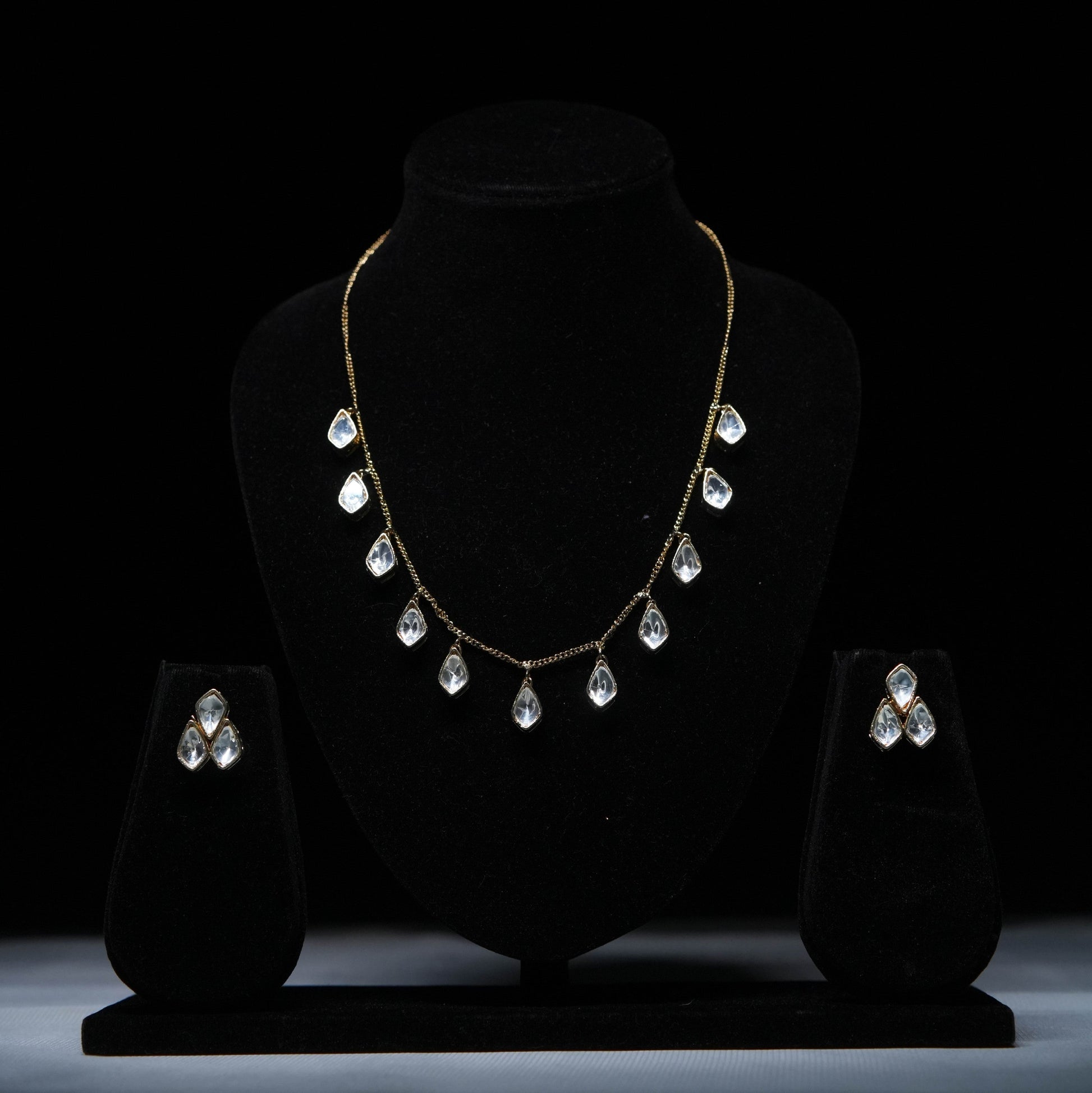 Classic teardrop Polki diamond necklace set with matching earrings displayed on black stand