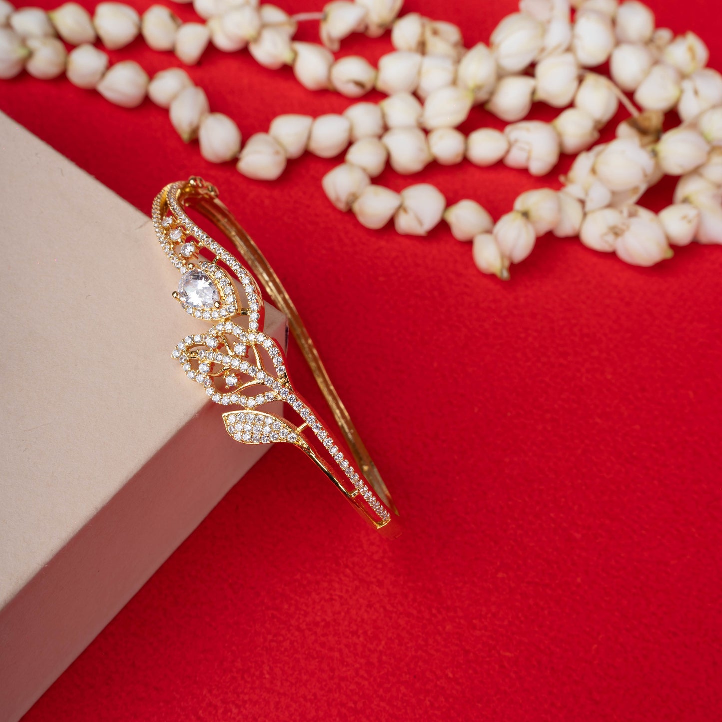 Gold floral stone-studded bracelet on display hand - Revaaj Ground