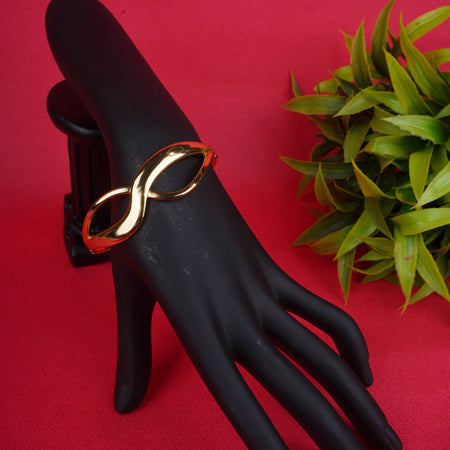 Gold-tone cuff bracelet with infinity symbol design on a black display hand - Revaaj