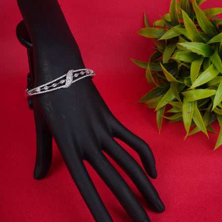 Silver crisscross cuff bracelet with sparkling stones on a black display hand - Revaaj