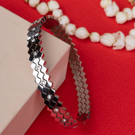 Silver zigzag bangle with embedded white stones on red background - Revaaj