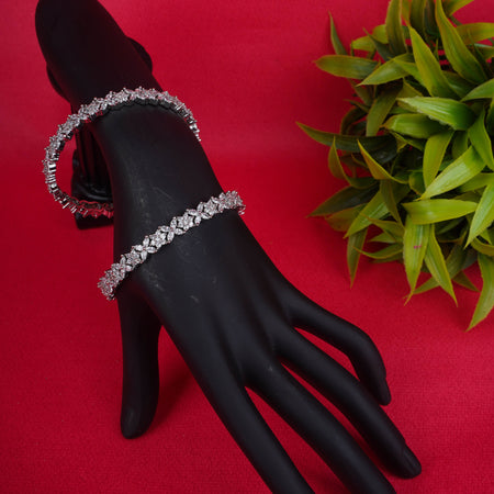 Silver floral vine stone bangle displayed on a black mannequin hand with red background - Revaaj