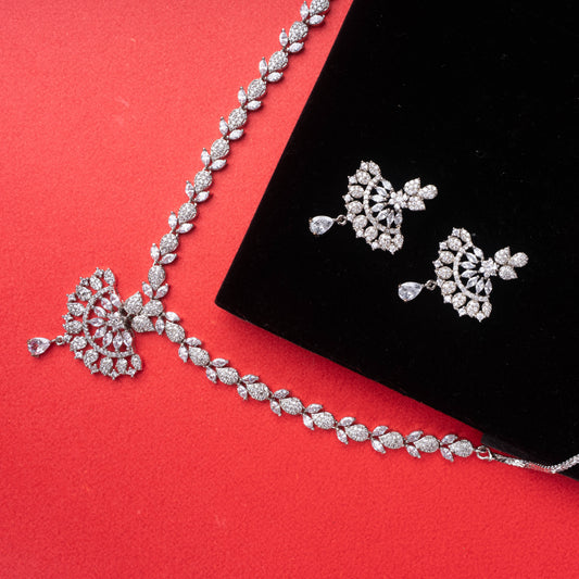Silver-tone fan design necklace and earrings set with clear synthetic stones on red background - Revaaj