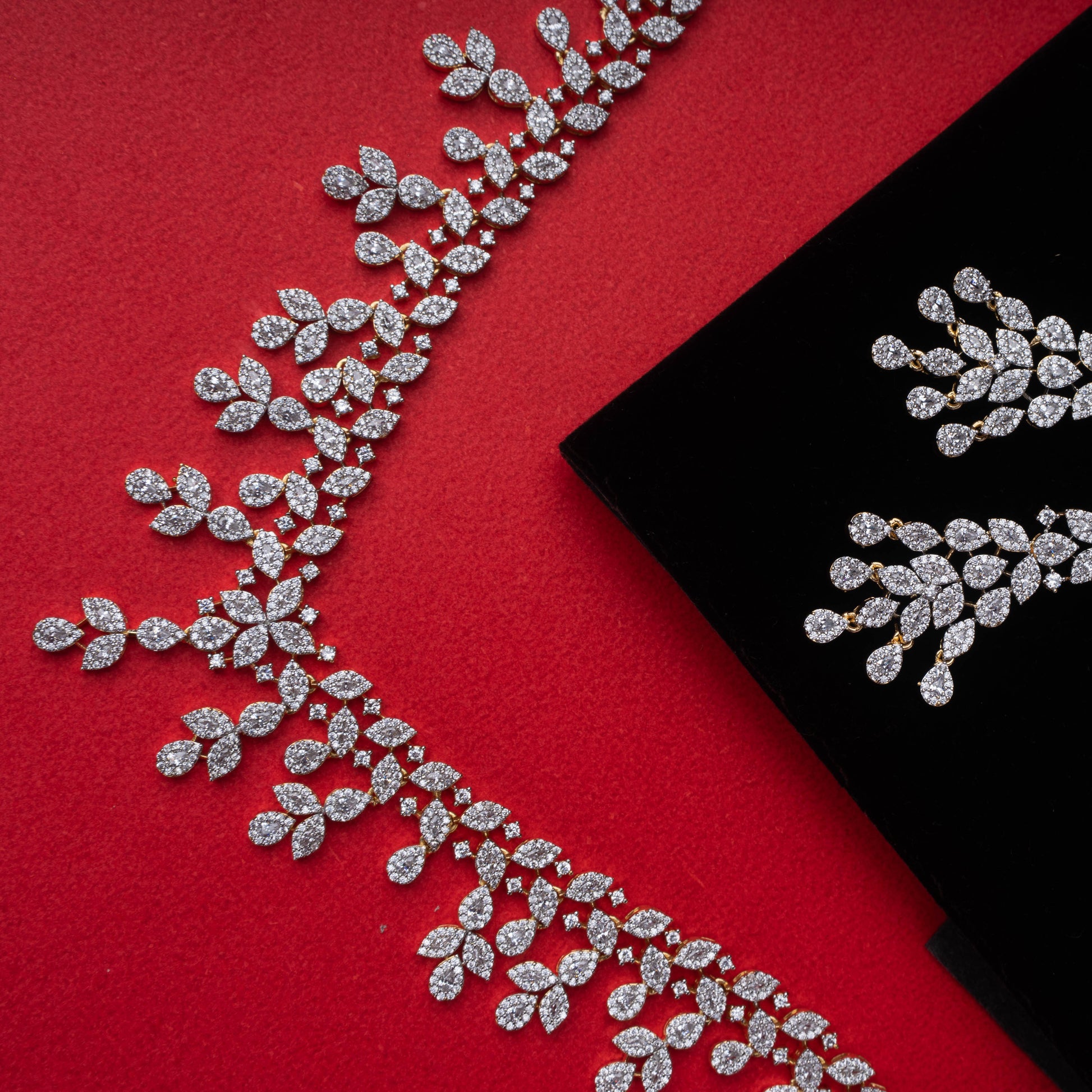 Silver-tone cascading leaf drop necklace and earrings set with synthetic stones on a black display - Revaaj Ground