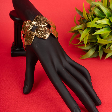 Wide gold-tone cuff bracelet with interlocking leaf motifs on a black mannequin hand - Revaaj