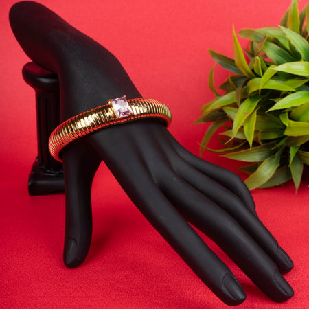 Gold-tone ribbed bangle bracelet with a single square-cut pink crystal - Revaaj