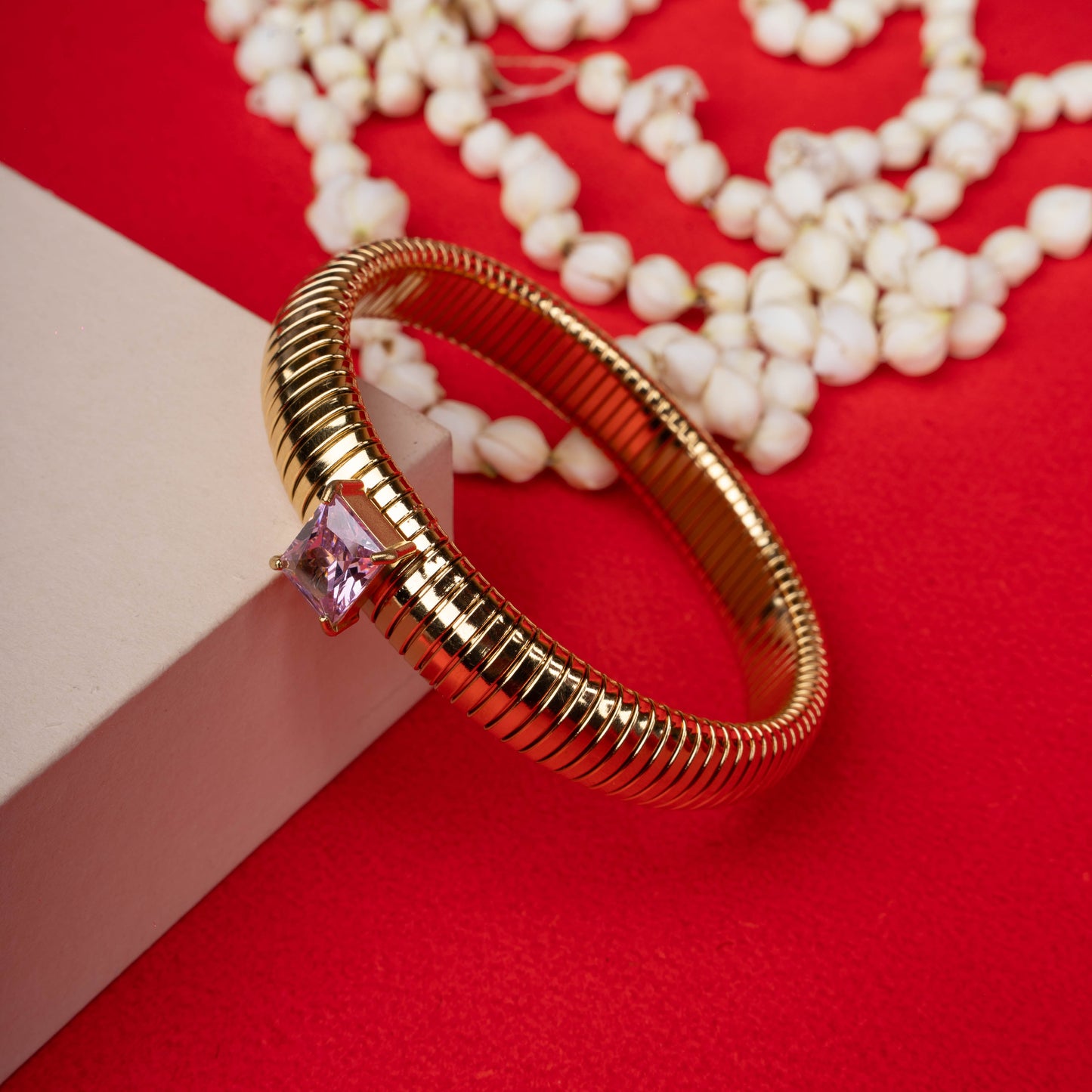 Gold-tone ribbed bangle bracelet with a single square-cut pink crystal ground - Revaaj