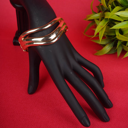 Gold-tone open cuff bracelet with a triple wave design, worn on a black mannequin hand - Revaaj