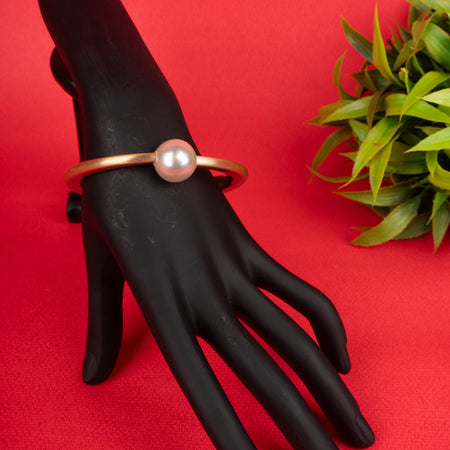 Gold-tone matte finish bangle bracelet with a single, large white pearl at the center - Revaaj