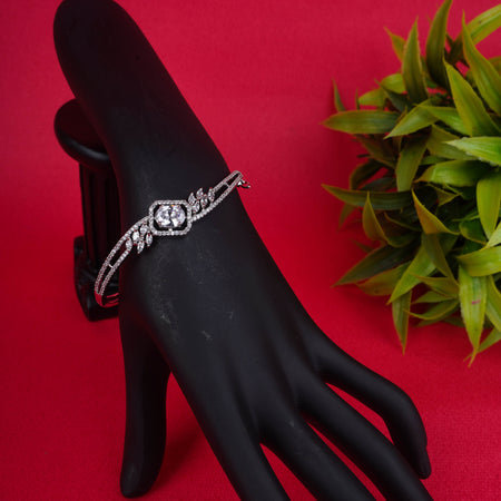 Ornate silver-tone hinged bracelet with a large oval-cut crystal at the center, surrounded by a halo of smaller crystals and winged accents - Revaaj