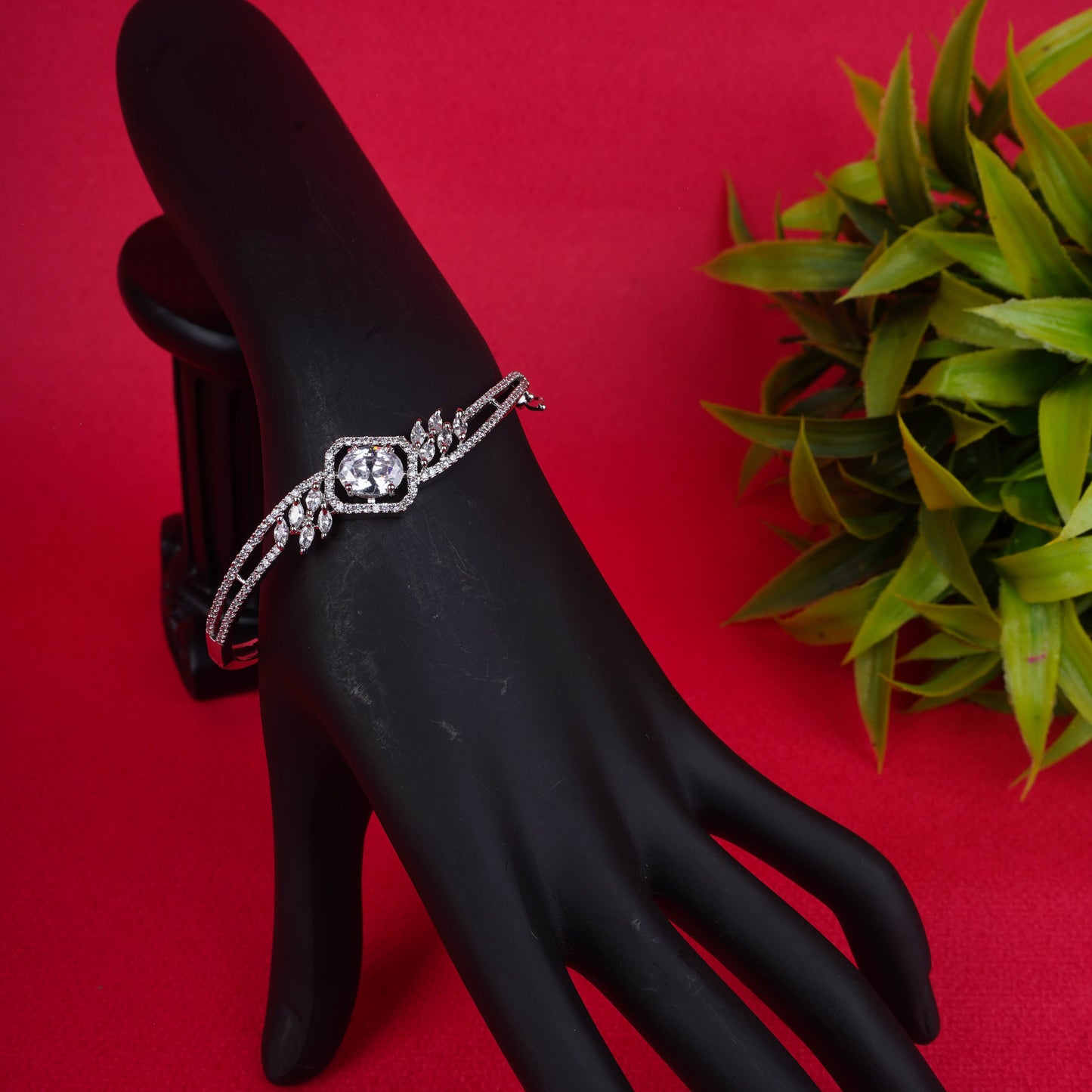 Ornate silver-tone hinged bracelet with a large oval-cut crystal at the center, surrounded by a halo of smaller crystals and winged accents - Revaaj