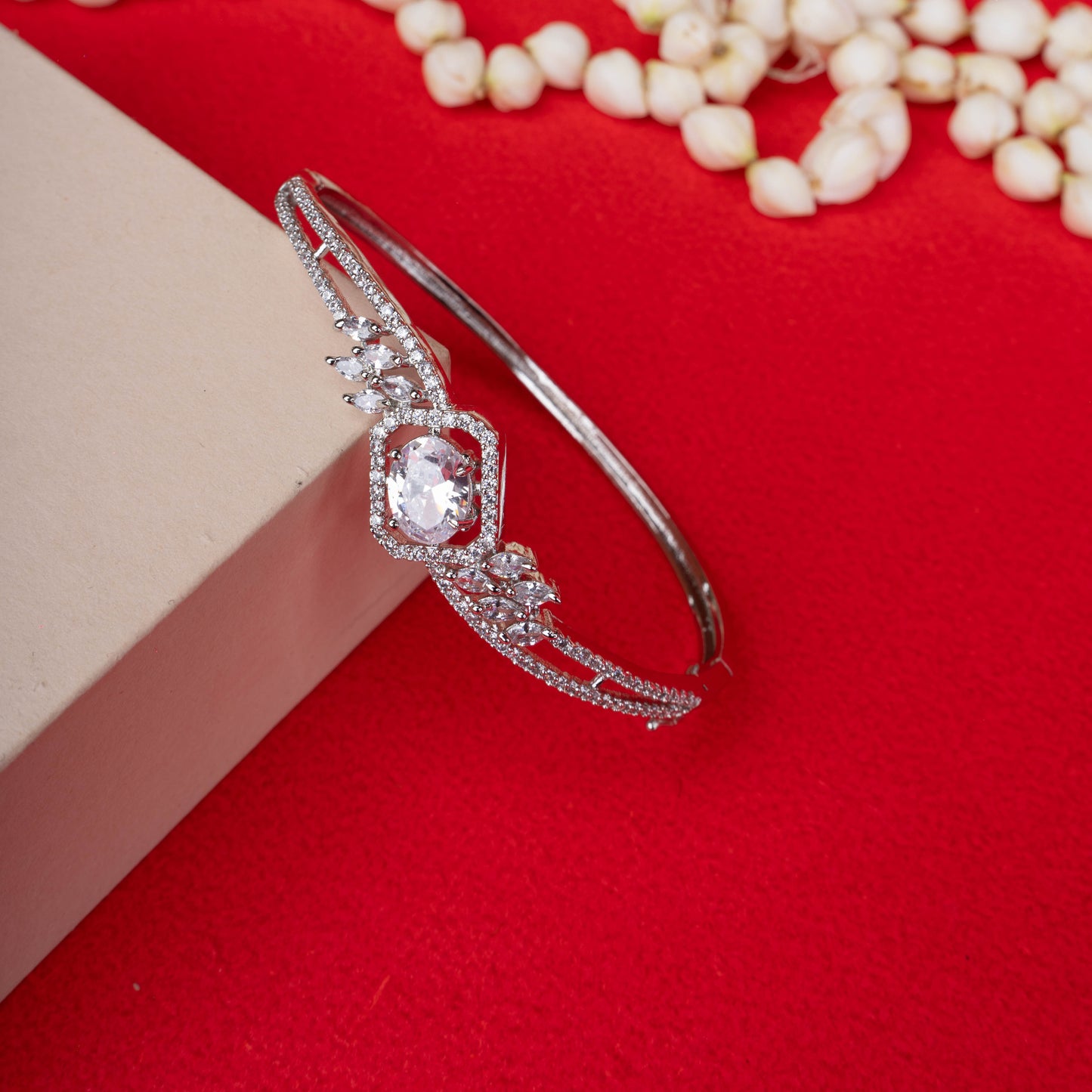 Ornate silver-tone hinged bracelet with a large oval-cut crystal at the center, surrounded by a halo of smaller crystals and winged accents ground image  - Revaaj
