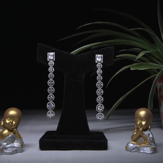 Elegant long drop earrings with square studs and cascading round crystal accents displayed on black stand