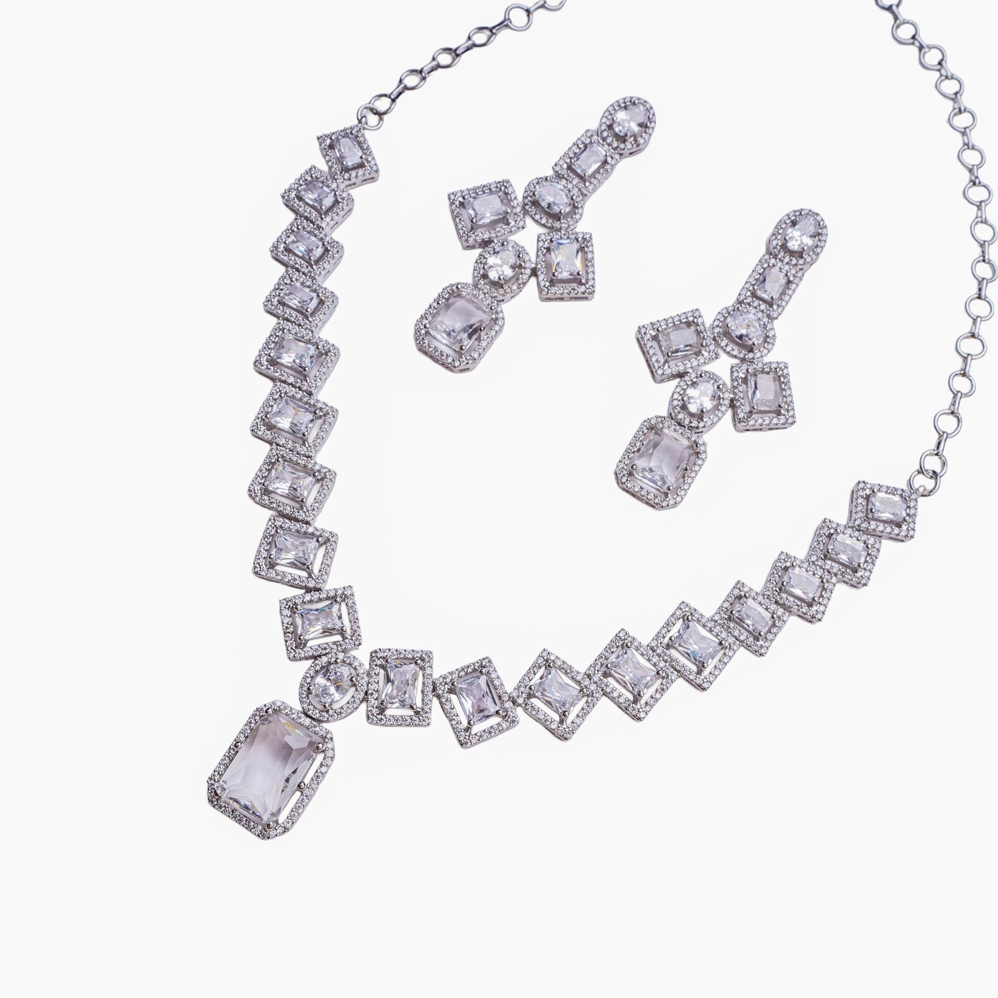 Necklace and earring set with square and oval clear stones in halo setting on white background