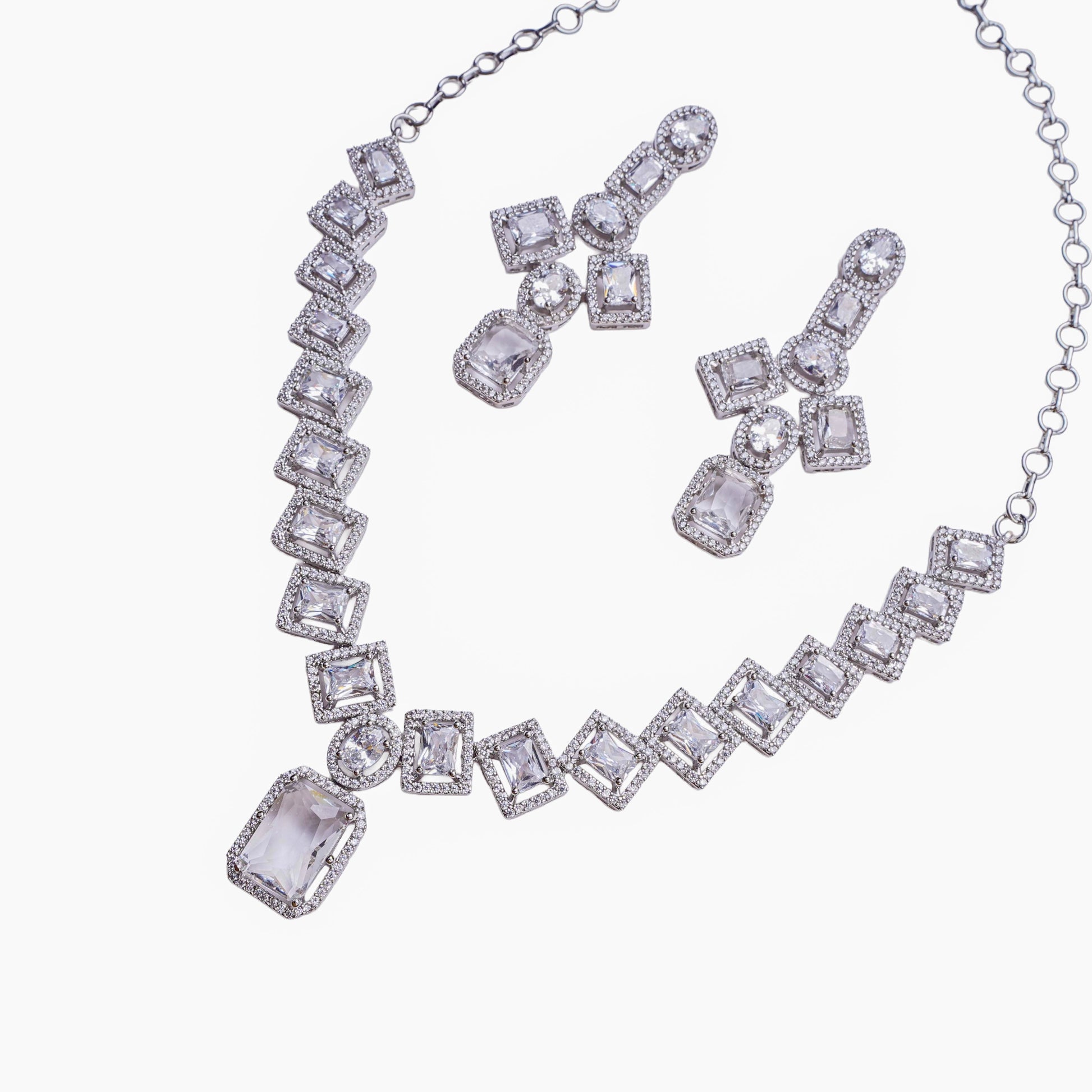 Necklace and earring set with square and oval clear stones in halo setting on white background