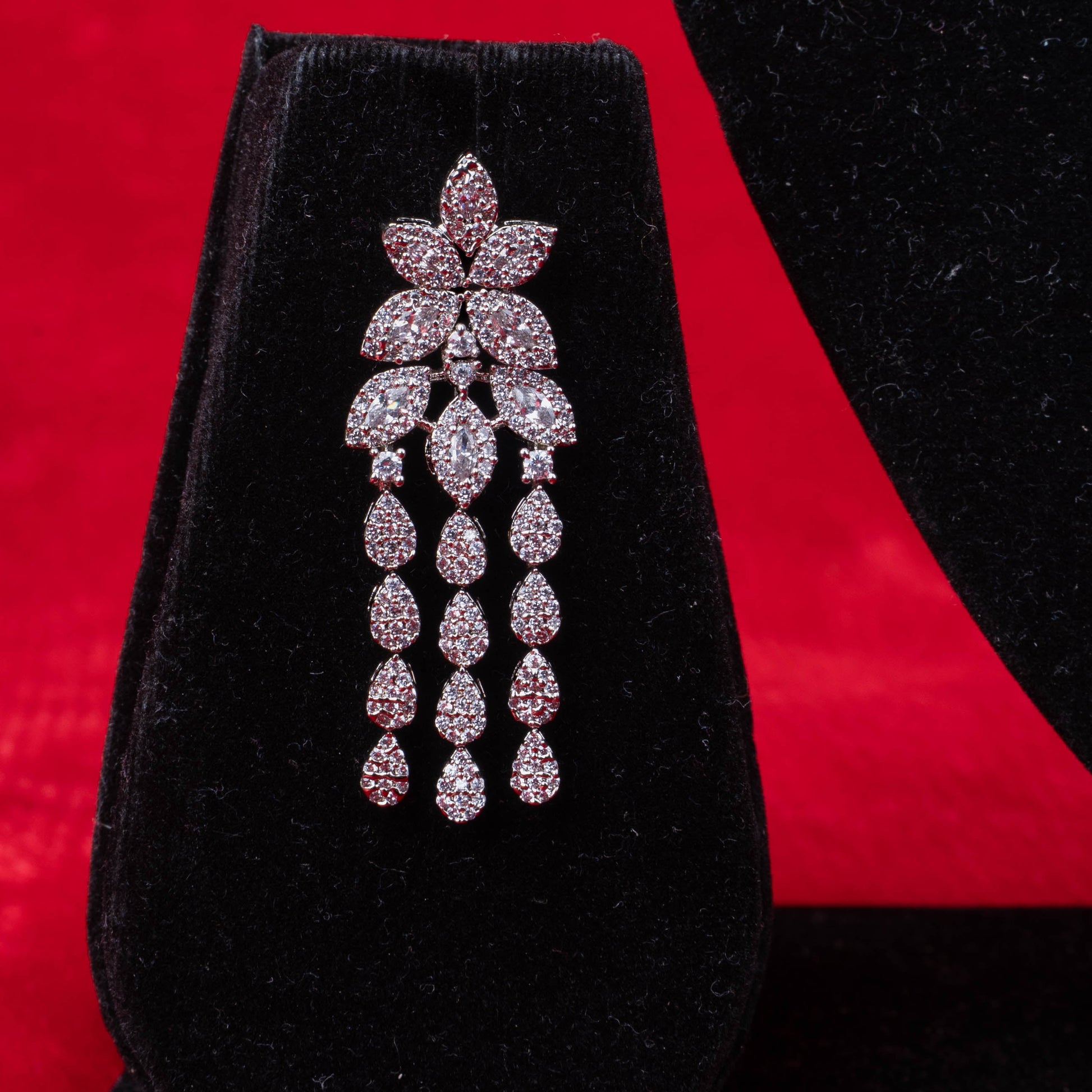 Floral cluster earring with cascading teardrop-shaped stones in silver-tone setting on black display