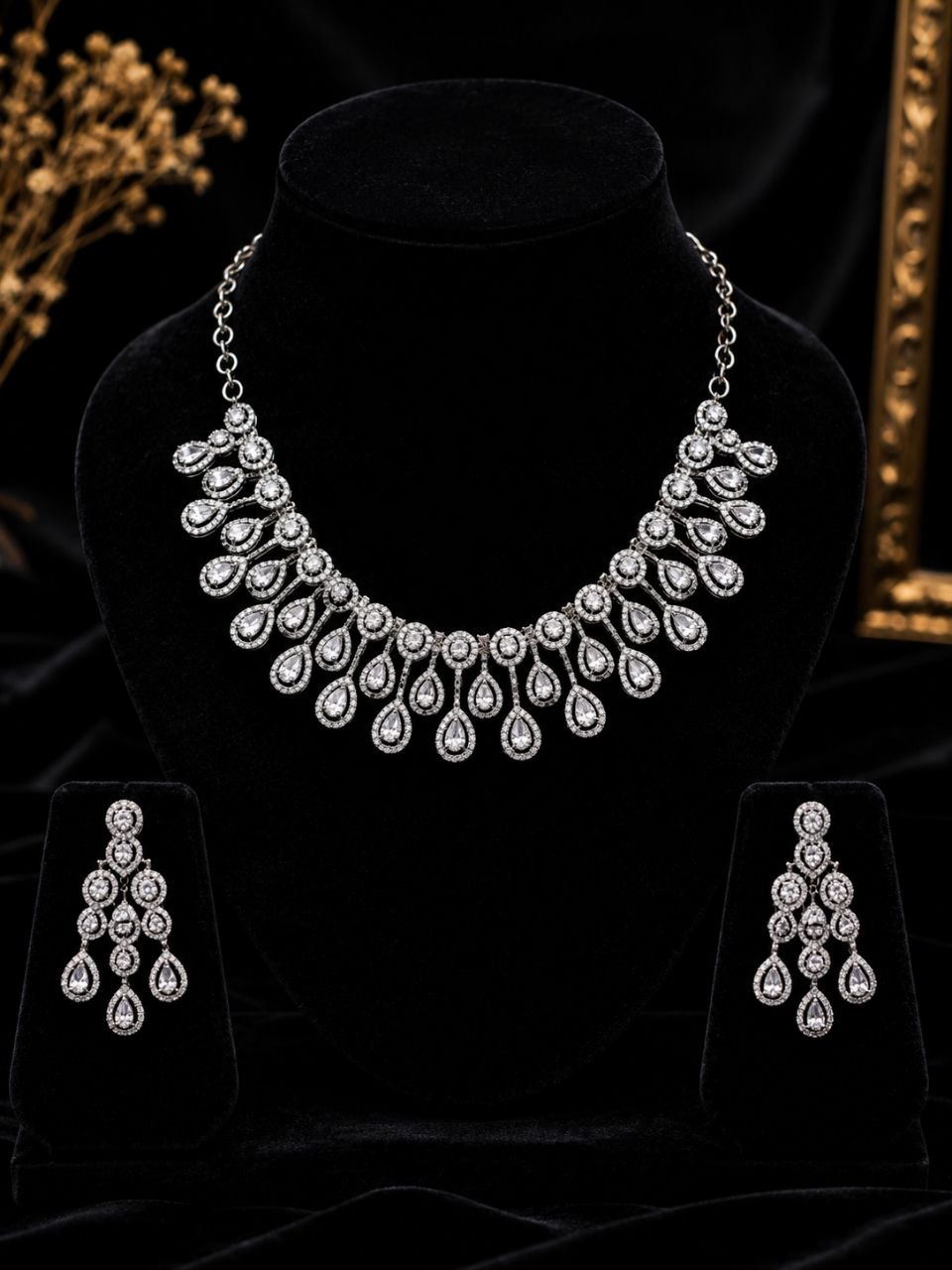 Luxury silver teardrop American diamond necklace and matching earrings set displayed on beige jewelry bust with soft beige background 3