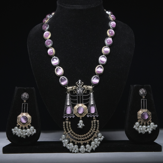 Revaaj Kundan necklace set with lavender gemstones and pearl earrings displayed on a black jewelry stand.