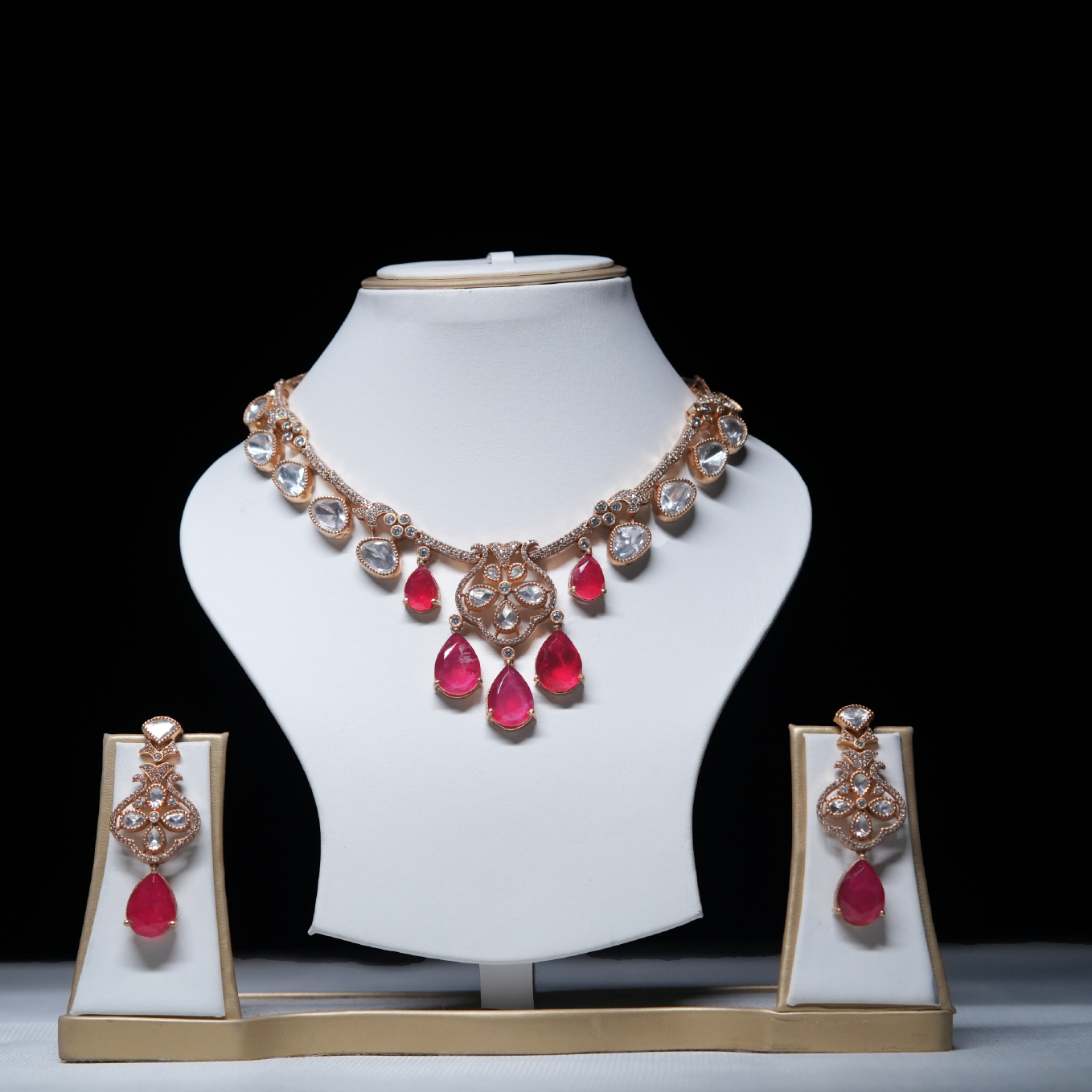 Revaaj Kundan necklace set with red and white gemstones displayed on a mannequin.  The set includes a necklace and matching earrings.