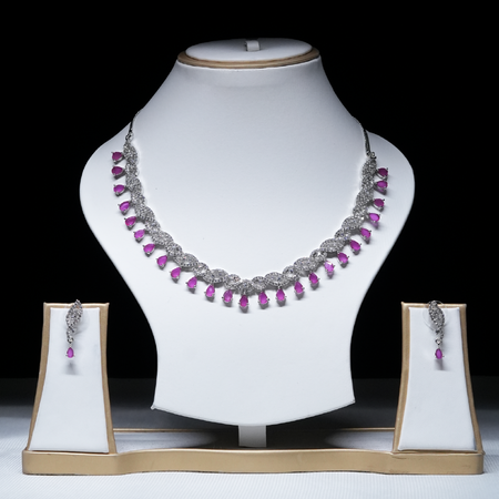 Revaaj pink ruby and white cubic zirconia necklace set displayed on a white jewelry stand, showcasing the necklace and matching earrings.