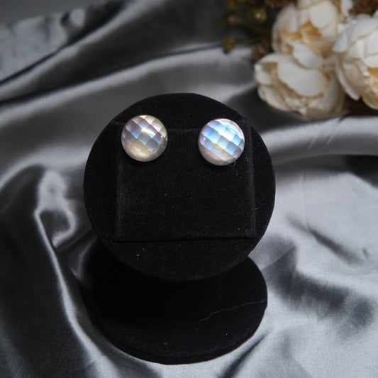Moonstone stud earrings with polished silver frame displayed on black velvet stand.