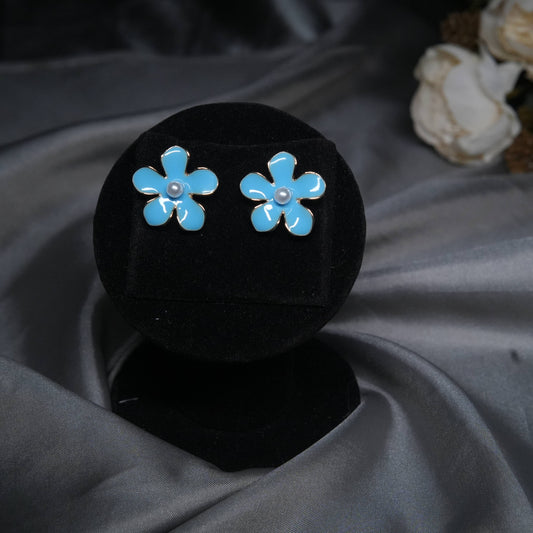 Sky blue floral enamel stud earrings with pearl center displayed on black velvet stand.