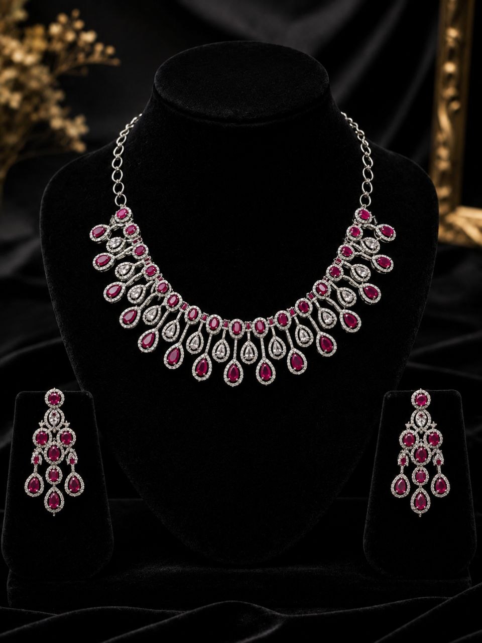 Elegant ruby red and clear stone teardrop necklace with matching dangling earrings on black velvet bust display 1