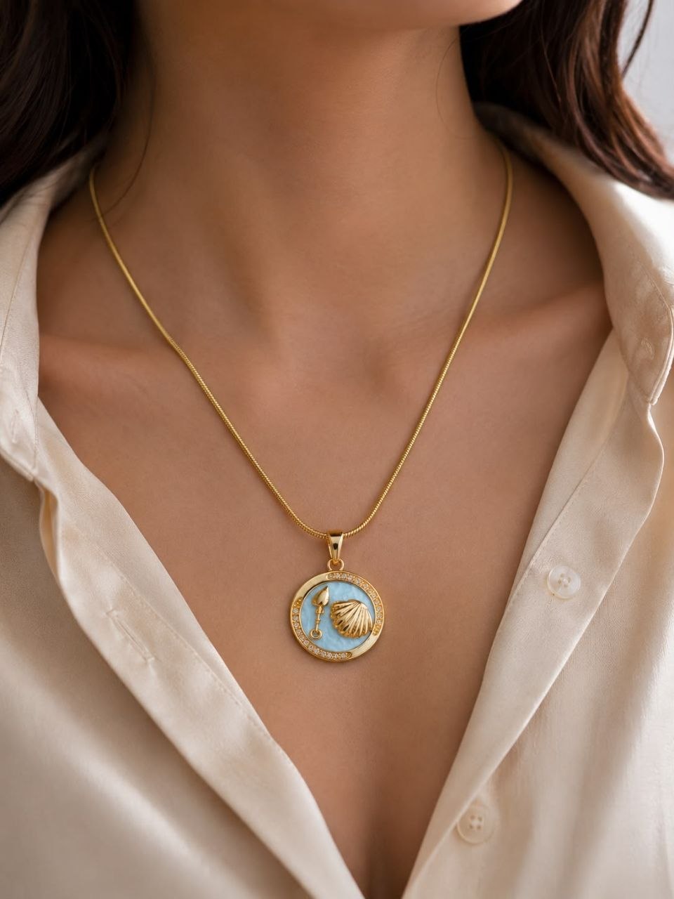 Gold plated necklace with circular light blue enamel pendant featuring golden seashell and spade charm surrounded by sparkling crystals on snake chain 2