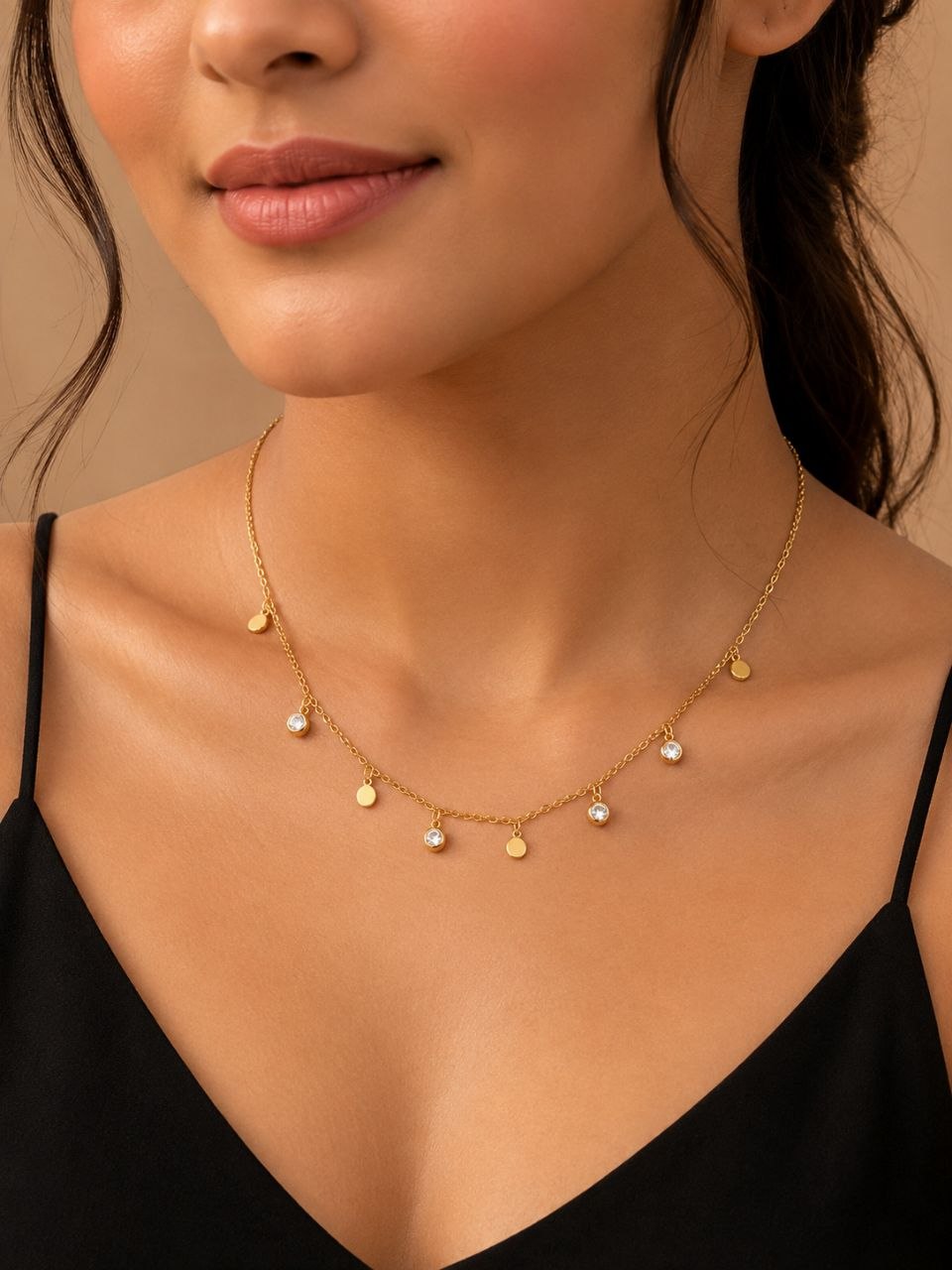 Delicate gold necklace with multiple circular charms and three clear crystal pendants displayed on beige fabric background 2