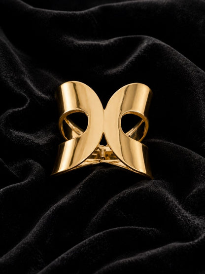 Shiny gold bow-shaped metallic hair claw clip displayed on white satin fabric 3
