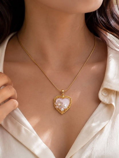 Gold heart-shaped pendant necklace with pink center, iridescent floral crystals, white pearls, and delicate chain on white background 2