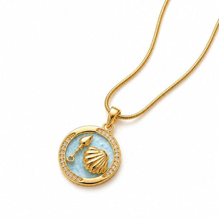Gold plated necklace with circular light blue enamel pendant featuring golden seashell and spade charm surrounded by sparkling crystals on snake chain 1