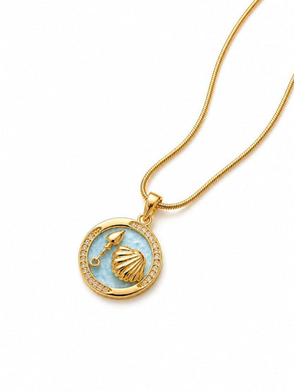 Gold plated necklace with circular light blue enamel pendant featuring golden seashell and spade charm surrounded by sparkling crystals on snake chain 1