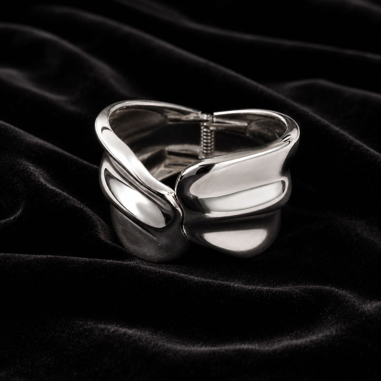 Polished silver abstract wavy sculptural statement ring displayed on soft beige silk fabric 3
