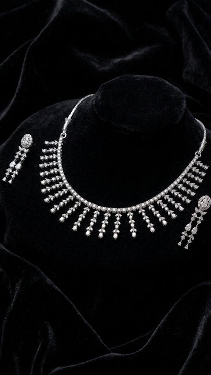 Premium silver fringe necklace with cascading crystal tassels and matching drop earrings displayed on white velvet fabric 3