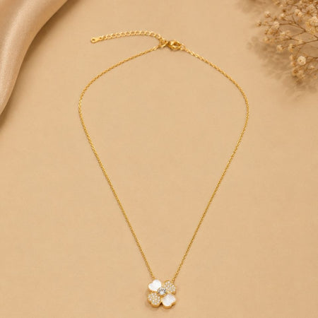 Delicate gold chain necklace with white four-petal floral pendant featuring sparkling crystal stones on beige background 1