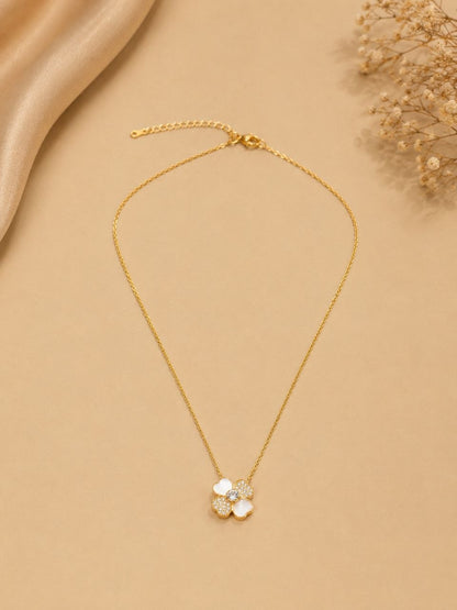 Delicate gold chain necklace with white four-petal floral pendant featuring sparkling crystal stones on beige background 1