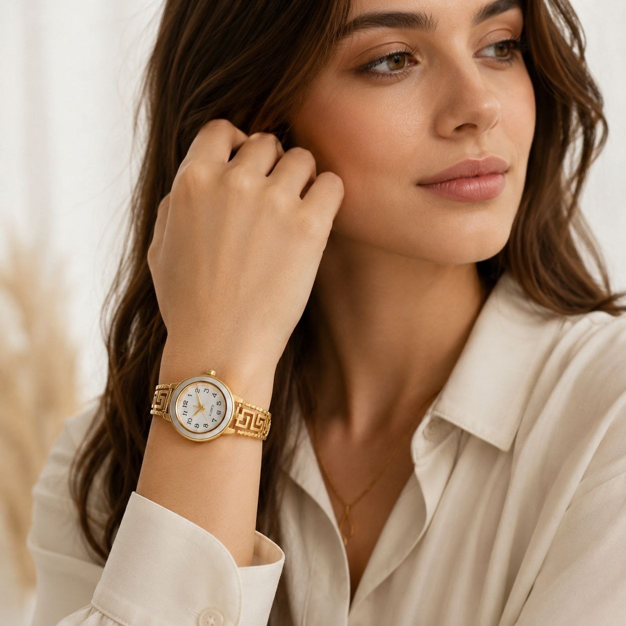 Gold women's bangle watch with intricate Greek key pattern on the band and luxurious mother-of-pearl dial featuring gold hands and markers 2