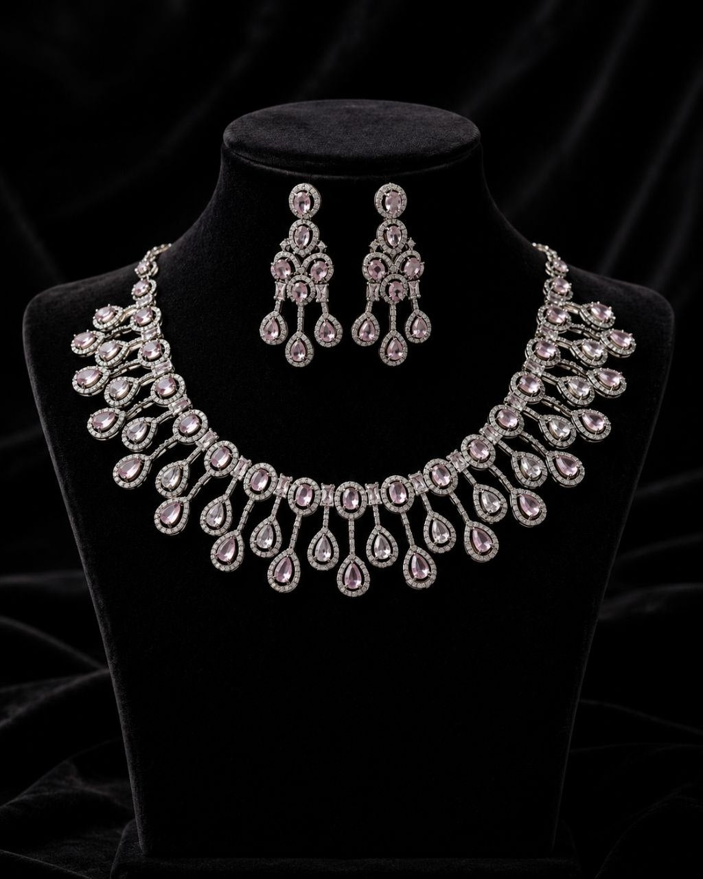 Elegant silver-plated necklace with pink teardrop cubic zirconia stones and matching chandelier earrings displayed on a beige jewelry bust against a soft beige background 3