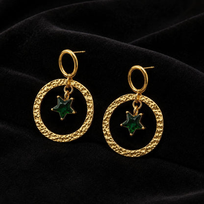 Pair of gold hammered circular hoop earrings with dangling green star crystal pendants on white background 3