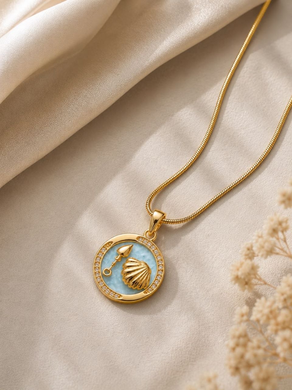 Gold plated necklace with circular light blue enamel pendant featuring golden seashell and spade charm surrounded by sparkling crystals on snake chain 3