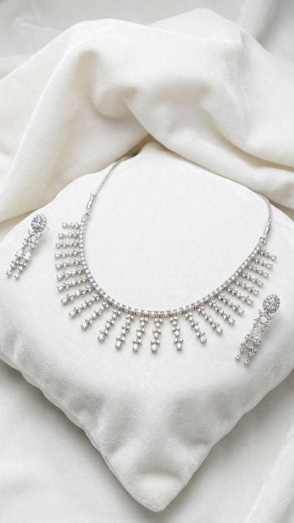 Premium silver fringe necklace with cascading crystal tassels and matching drop earrings displayed on white velvet fabric 1