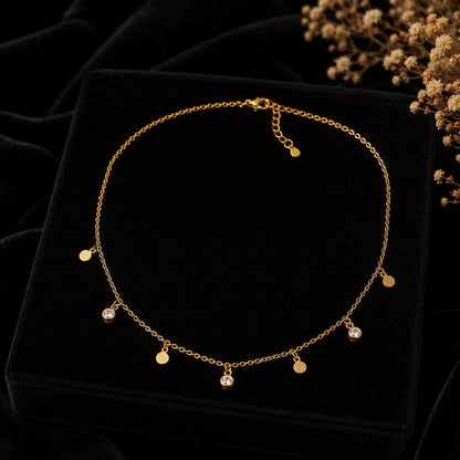 Delicate gold necklace with multiple circular charms and three clear crystal pendants displayed on beige fabric background 3