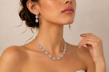 Silver-toned necklace with multiple oval pink gemstones in pave settings paired with matching drop earrings displayed on a beige jewelry bust 3