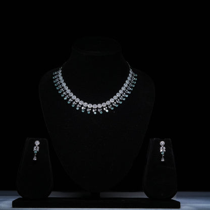Elegant emerald drop diamond necklace set with matching earrings on black display 