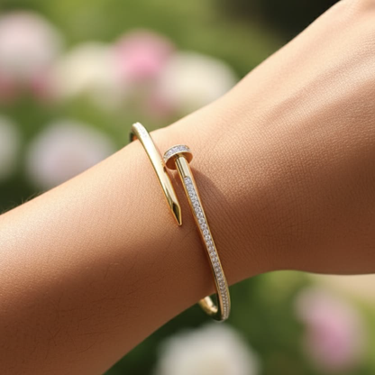 Gold nail design bracelet with diamond accents on beige satin fabric stand