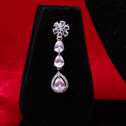 Diamond floral and teardrop dangle earring on black velvet with red background