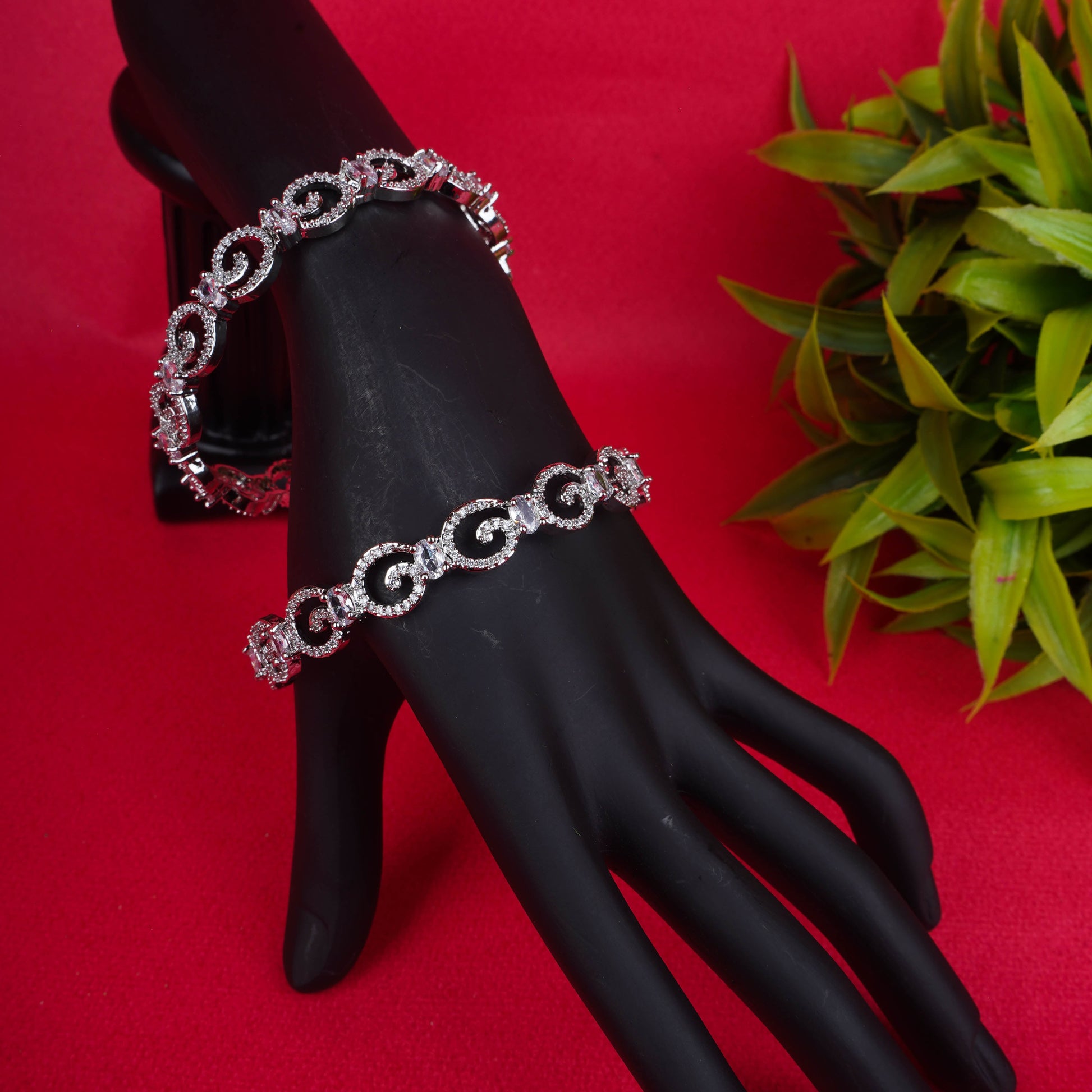 Silver loop crystal bangles on a black mannequin hand - Revaaj